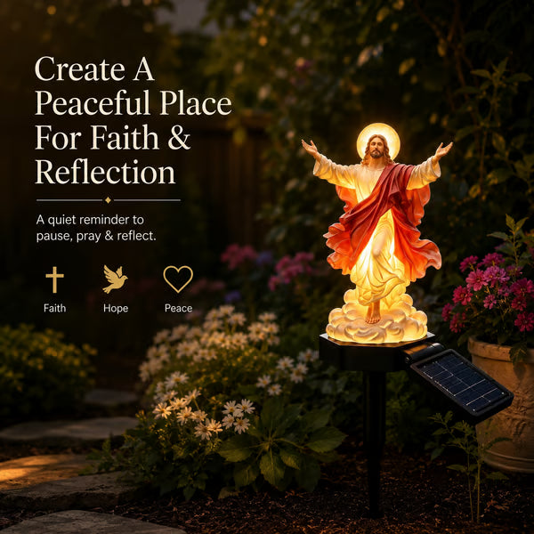 Illuminated Jesus statue beside flowers and a stone garden path, creating a quiet evening focal point